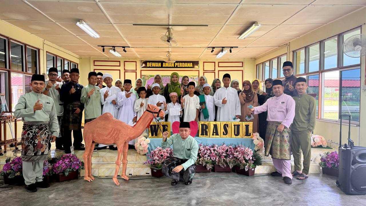 Guru dan murid yang terlibat dengan sambutan Maulidul Rasul bergambar kenangan di dewan utama sekolah.