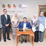 Mohd Afandi (duduk) ketika menandatangani buku pelawat ketika sesi ke Kunjungan Hormat UniMAIWP ke UPSI Kampus Sultan Abdul Jalil Shah.