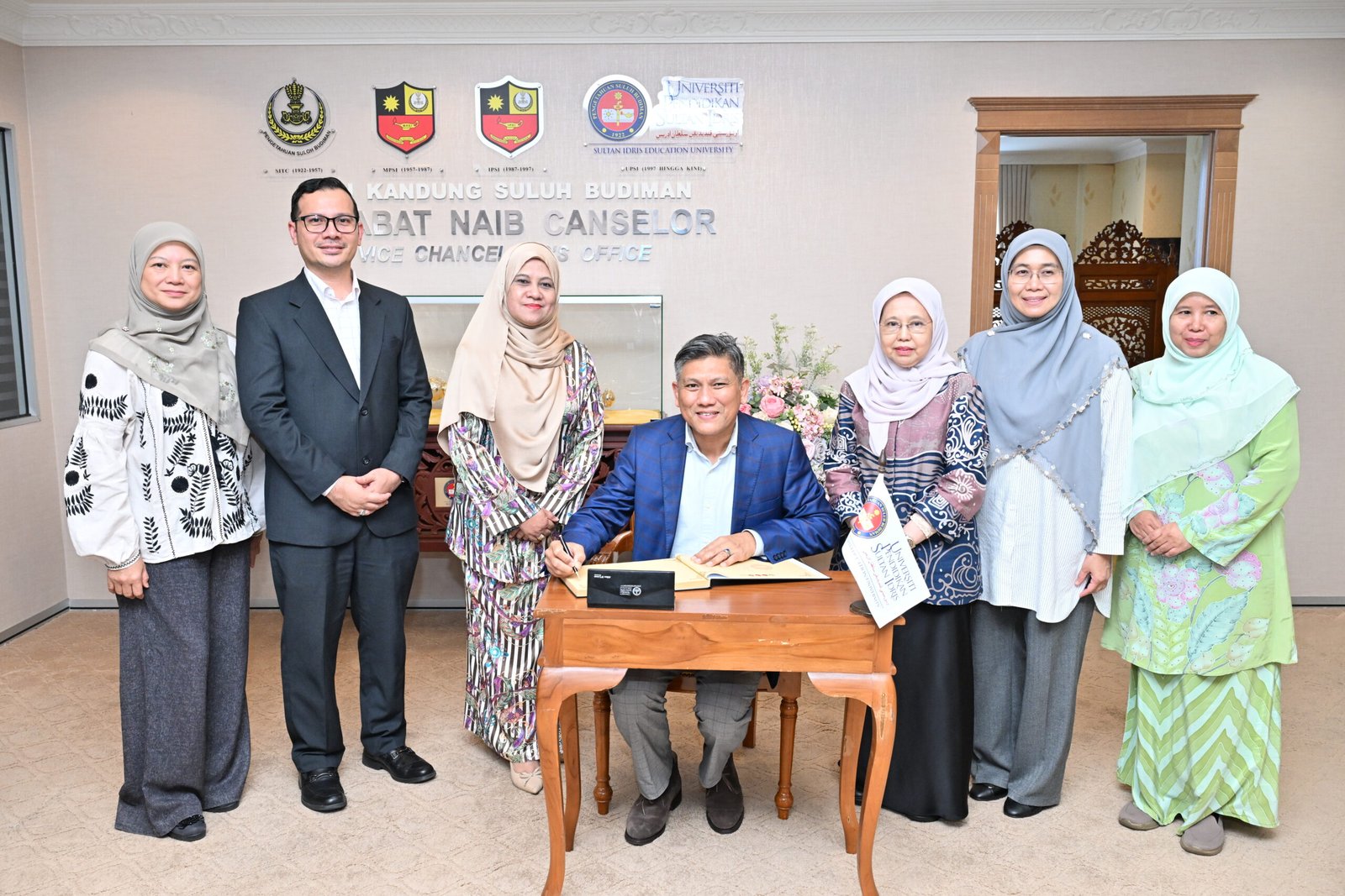 Mohd Afandi (duduk) ketika menandatangani buku pelawat ketika sesi ke Kunjungan Hormat UniMAIWP ke UPSI Kampus Sultan Abdul Jalil Shah.